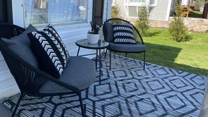 A patio with two black chairs, a small table, and a patterned rug. - Pet Friendly, Extended Stay 30+ (Johnson City)
