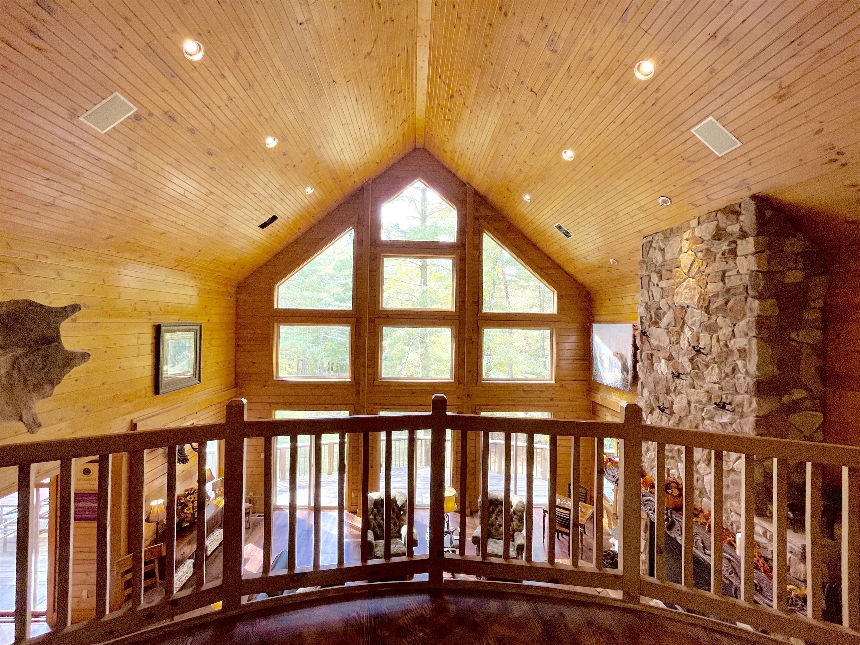 A spacious interior with high wooden ceilings, large windows, and a stone wall.
