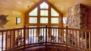 Un intérieur spacieux avec de hauts plafonds en bois, de grandes fenêtres et un mur en pierre.