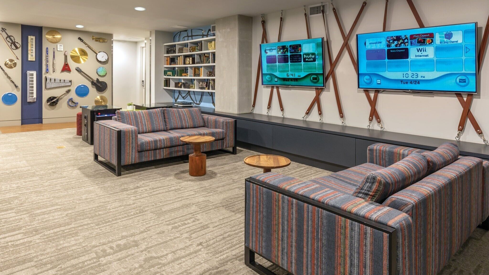 A modern lounge area with striped sofas, a coffee table, and a bookshelf filled with books and decorative items.