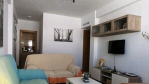 A living room with a sofa, a coffee table, a TV, and built-in shelves. - Amplio, Luminoso y Confortable; 15 Minutos del Centro (Málaga)