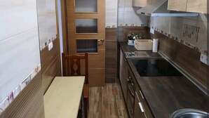 A compact kitchen with a wooden door, a sink, and a stove. - Amplio, Luminoso y Confortable; 15 Minutos del Centro (Málaga)
