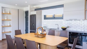 A modern kitchen with a wooden dining table, chairs, and built-in appliances. - BITTER ALMOND TREES VILLAS - Stylish villa, sea views 1000m from Nikiana & Beach (Lefkada)