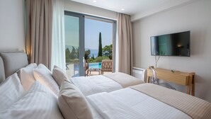 A hotel room with two beds, a TV, and a view of a pool and greenery. - BITTER ALMOND TREES VILLAS - Stylish villa, sea views 1000m from Nikiana & Beach (Lefkada)