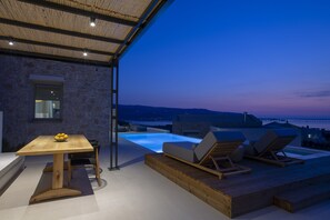 A rooftop terrace with a pool, lounge chairs, and a dining table.
