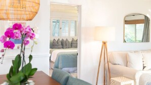 Habitación de hotel con cama, sofá, lámpara de pie y ventana con persianas.