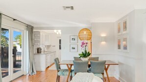 Una cocina moderna con armarios blancos y un comedor con mesa y sillas.