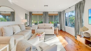 Una sala moderna con un conjunto de sofás, una mesa de centro y vistas al exterior a través de amplios ventanales.