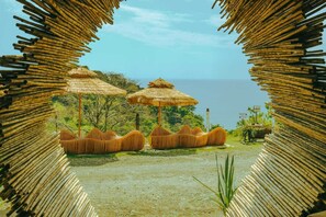A beach view with thatched umbrellas and bamboo seating. - Casa Lamia (Quepos)