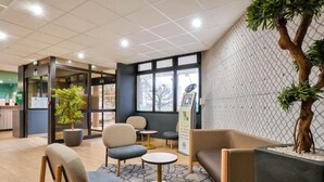 A modern lobby with seating areas, a reception desk, and a large window. - B&B Hotel Paris Rosny-sous-bois (Rosny-sous-Bois)