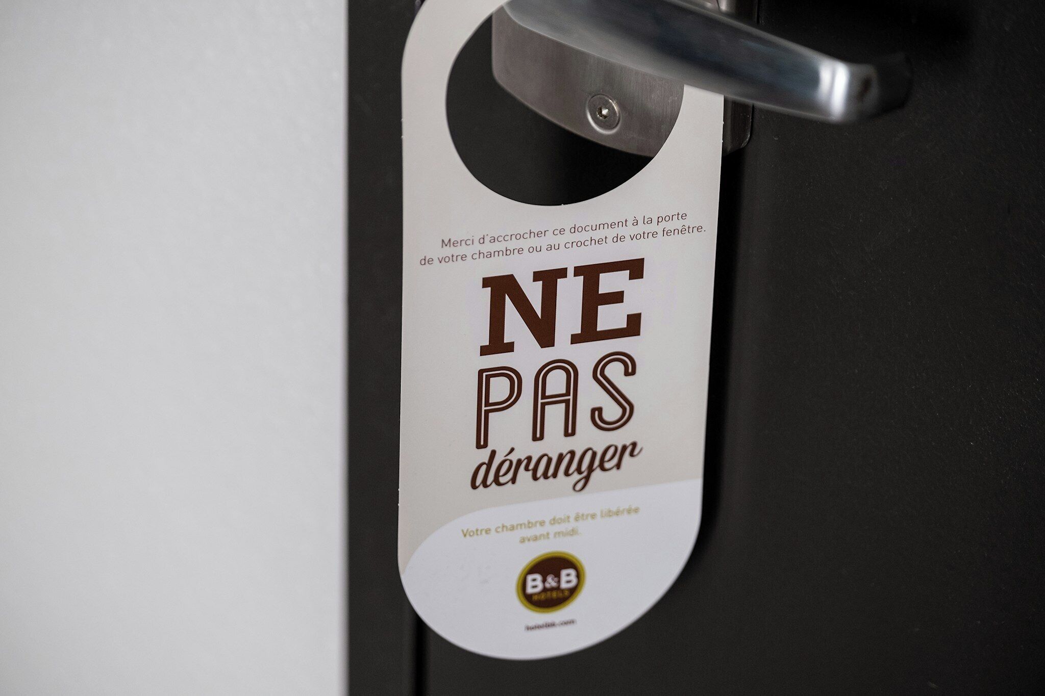 Een deur met een bord waarop 'NE PAS déranger' staat, en een logo van een B&B.