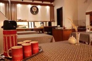 A hotel room with a bed, a table with red mugs, a teapot, and a clock on the wall. - Pousada Hencke Haus - Adults Only (Canela)