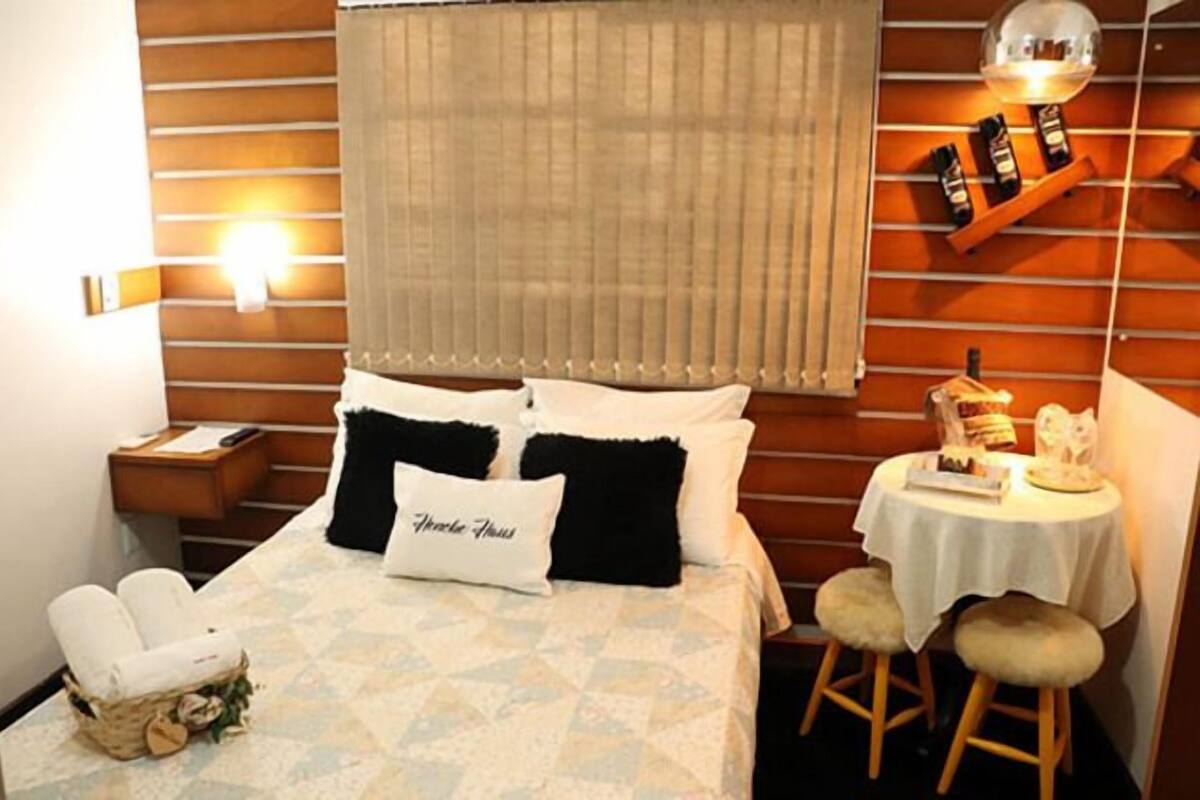 Ein Hotelzimmer mit einem Bett, einem Nachttisch, einer Nachttischlampe, einem kleinen Tisch ebenfalls mit einer Lampe und einem Sessel.