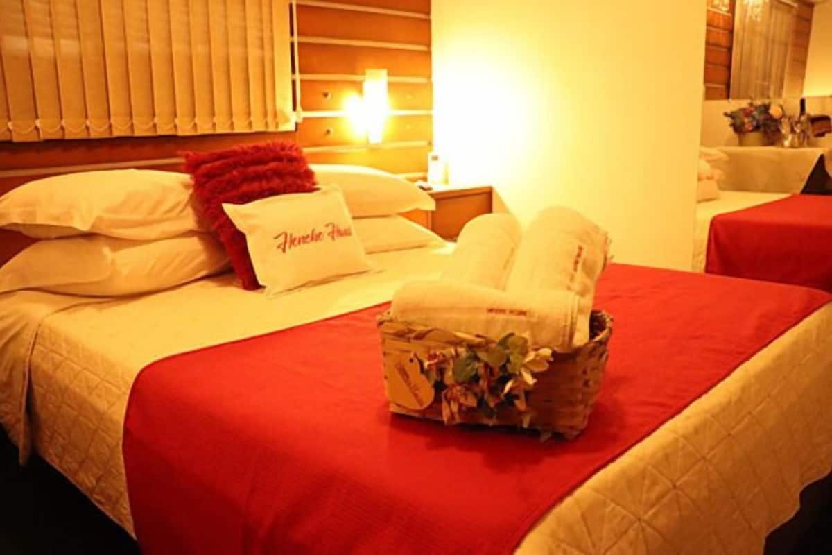 Ein Hotelzimmer mit einem Bett, einem Nachttisch, einer Lampe und einer roten Decke.