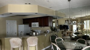 Uma cozinha moderna com ilha central, armários de madeira escura, micro-ondas e frigorífico.