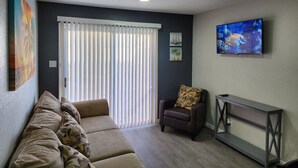 Un soggiorno con un divano, una poltrona, una televisione e un quadro appeso al muro.