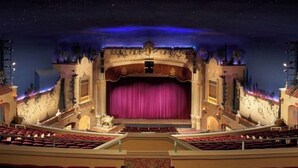 An indoor theater with a stage, auditorium seating, and ornate architectural details.