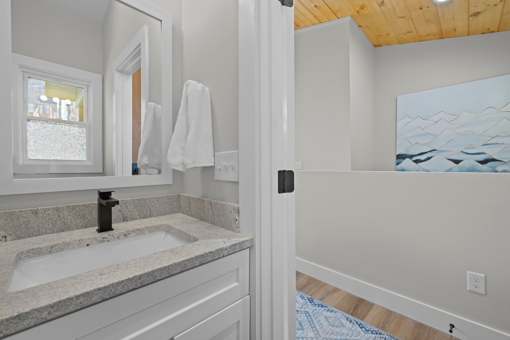 Une salle de bain avec un lavabo en granit, un miroir et une serviette accrochée au mur.
