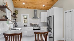 A modern kitchen with white cabinets, stainless steel appliances, and a wooden ceiling. - NEW Mountain Modern Hideaway! - Walk to Disc Golf (Marion)