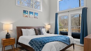 A bedroom with a large bed, two bedside tables, a window with curtains, and three wall-mounted pictures. - NEW Mountain Modern Hideaway! - Walk to Disc Golf (Marion)