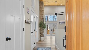 A hallway with white doors, a patterned rug, a ceiling fan, and a wooden wall. - NEW Mountain Modern Hideaway! - Walk to Disc Golf (Marion)