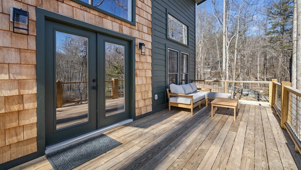 A wooden deck with a sofa and table, large sliding glass doors, and a view of trees. - NEW Mountain Modern Hideaway! - Walk to Disc Golf (Marion)