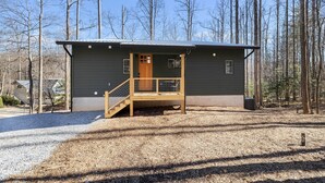 A small cabin with a wooden deck and a single door, surrounded by a forest. - NEW Mountain Modern Hideaway! - Walk to Disc Golf (Marion)