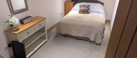 A bedroom with a bed, a dresser, a mirror, a lamp, and a radiator.
