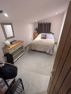 A bedroom with a bed, a dresser, a mirror, a lamp, and a radiator.