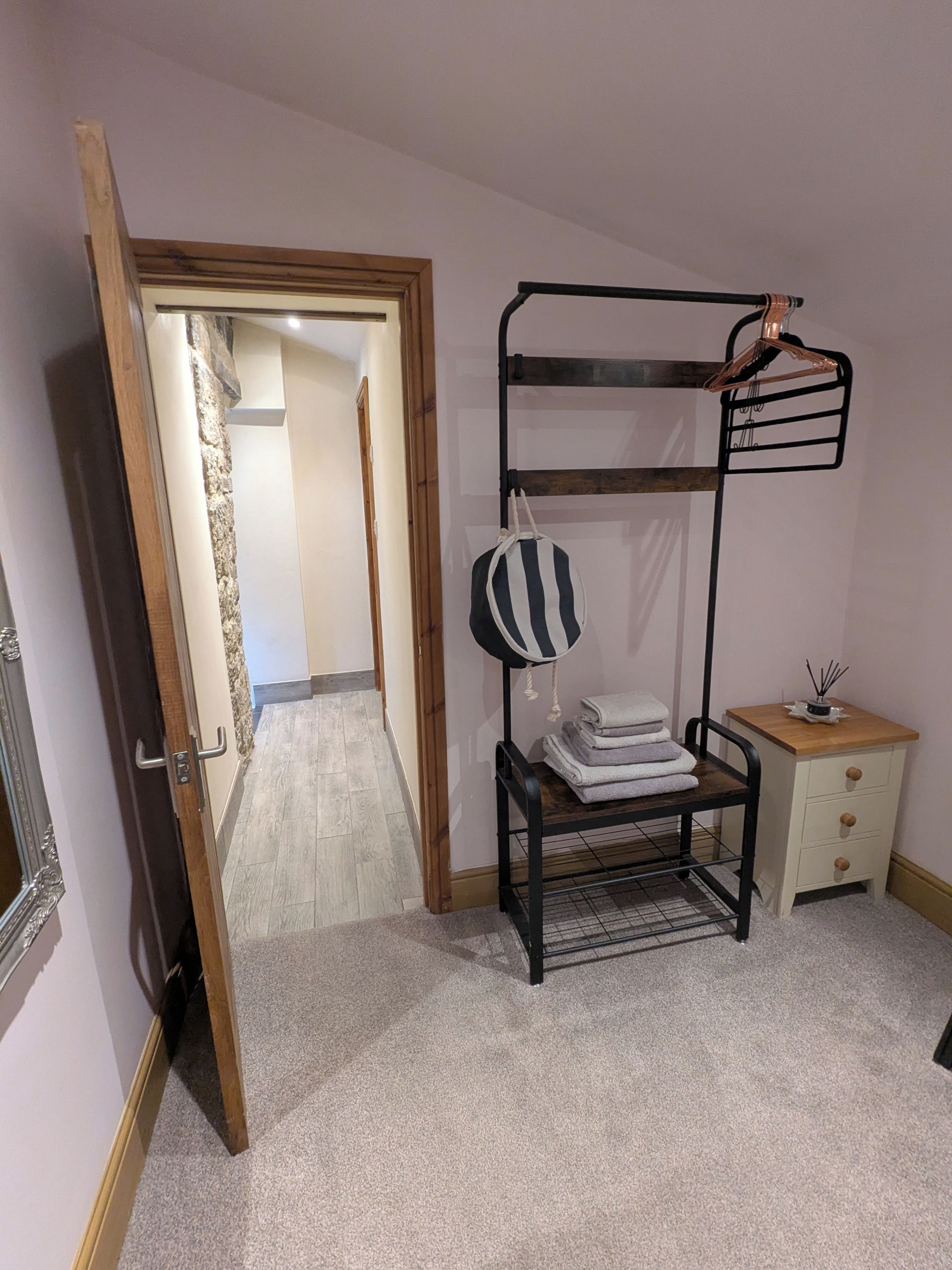 Ein Zimmer mit einem Etagenbett, einem kleinen Nachttischchen mit Lampe und einer Tür zu einem weiteren Raum.