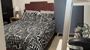 Un dormitorio con cama, mesita de noche, lámpara y decoración en la pared.