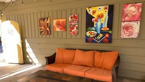 A cozy outdoor seating area with a wicker sofa and a wooden coffee table. - Maple Valley Hummingbird Studio (Maple Valley)