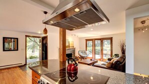 A modern kitchen with a central island, a built-in stove, and a large range hood.