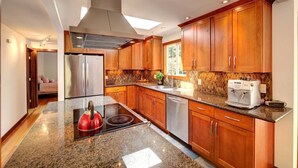 A modern kitchen with wooden cabinets, a stainless steel refrigerator, a built-in oven, and a coffee machine.