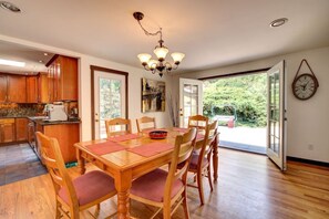 A spacious kitchen with wooden cabinets, a dining table with chairs, and a large window offering a view of the outdoors. - Central Sammamish Home With Private Setting (Sammamish)