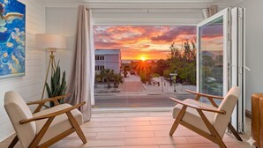 A room with a view of a sunset, two armchairs, a lamp, and a painting on the wall. - Gertrude's Siesta | Oceanview, 12-steps Beach, 4-min trolley to Village, tiki-bar, ping-pong! (Siesta Key)