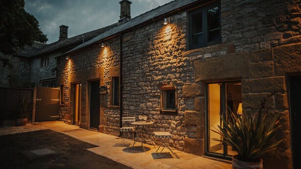 A stone building with a patio area, outdoor seating, and a potted plant. - The Piggery - stylish barn conversion in the heart of the High Peak (Tideswell)