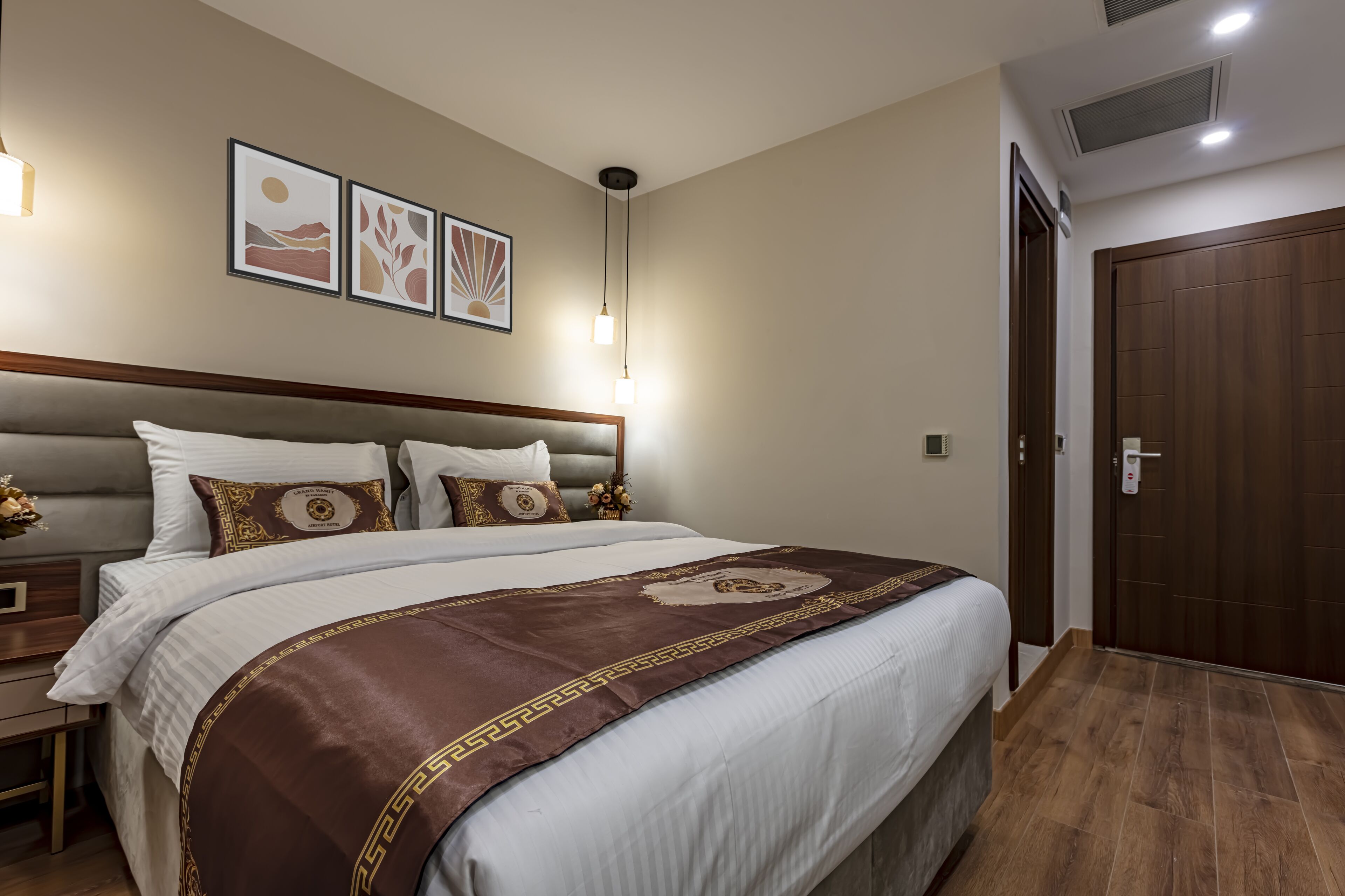 A neatly arranged hotel room with a large bed, a bedside table, and a wardrobe.