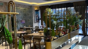 Een moderne hotellobby met een receptiebalie, een zithoek en grote ramen.