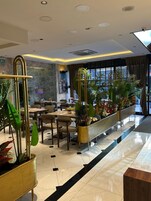 Un moderno vestíbulo de hotel con una recepción, zona de estar y grandes ventanales.