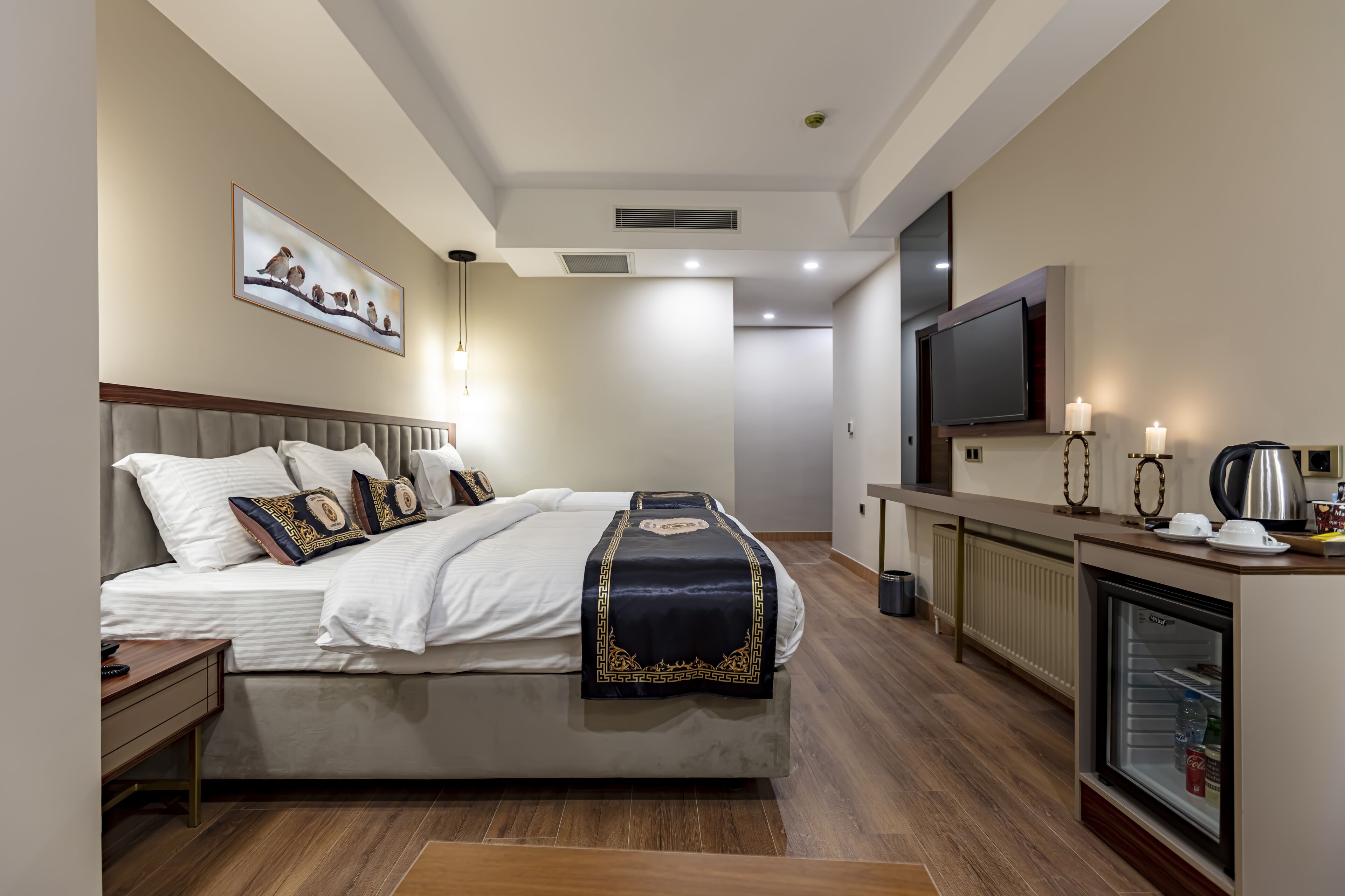 Een moderne hotelkamer met een bed, nachtkastje, lamp, televisie en een minibars.