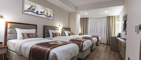 A hotel room with four beds, a painting of birds on the wall, and a view of the city.