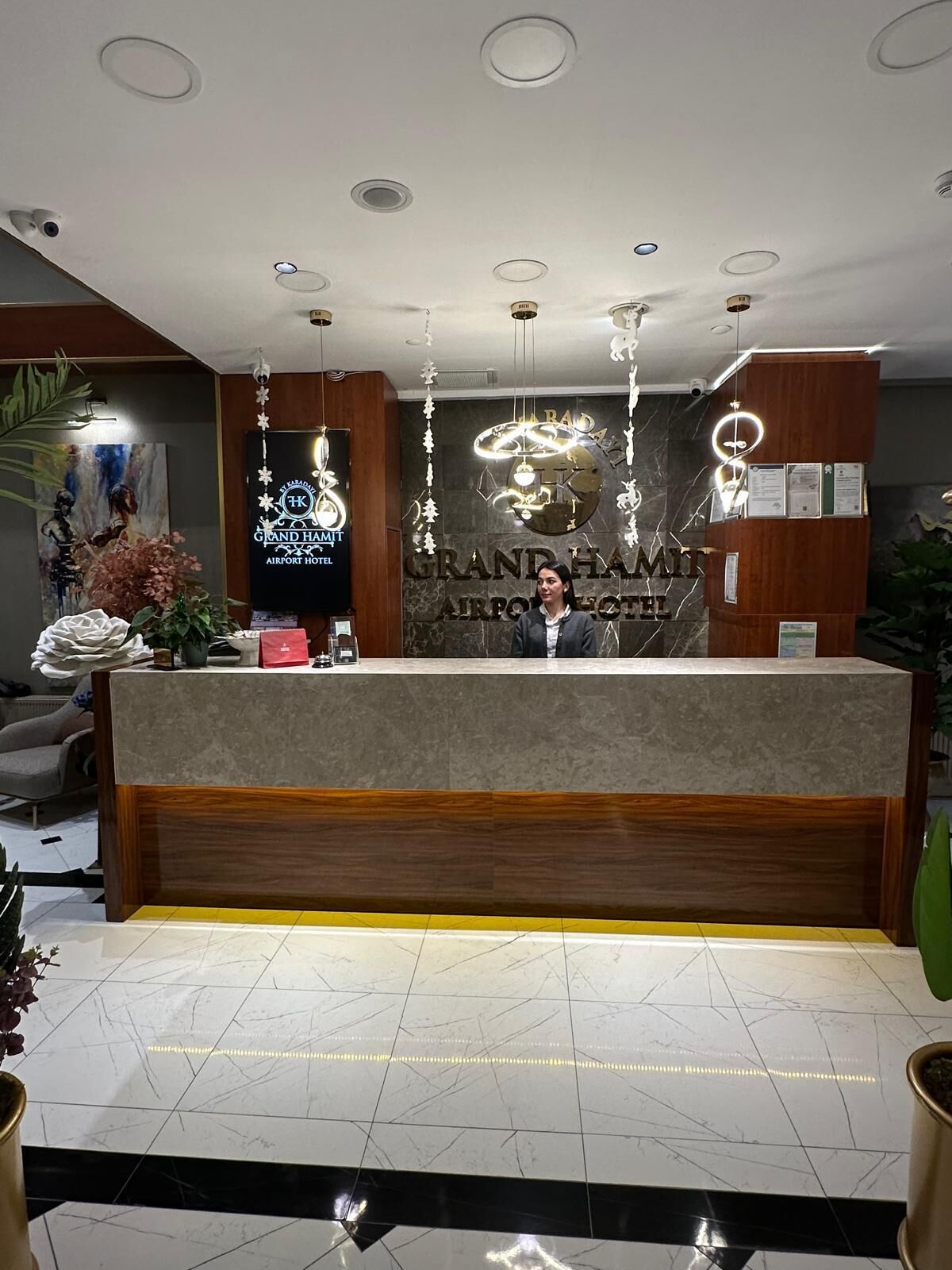 A hotel reception desk with a marble floor, a wooden reception desk, and a large sign above the desk.