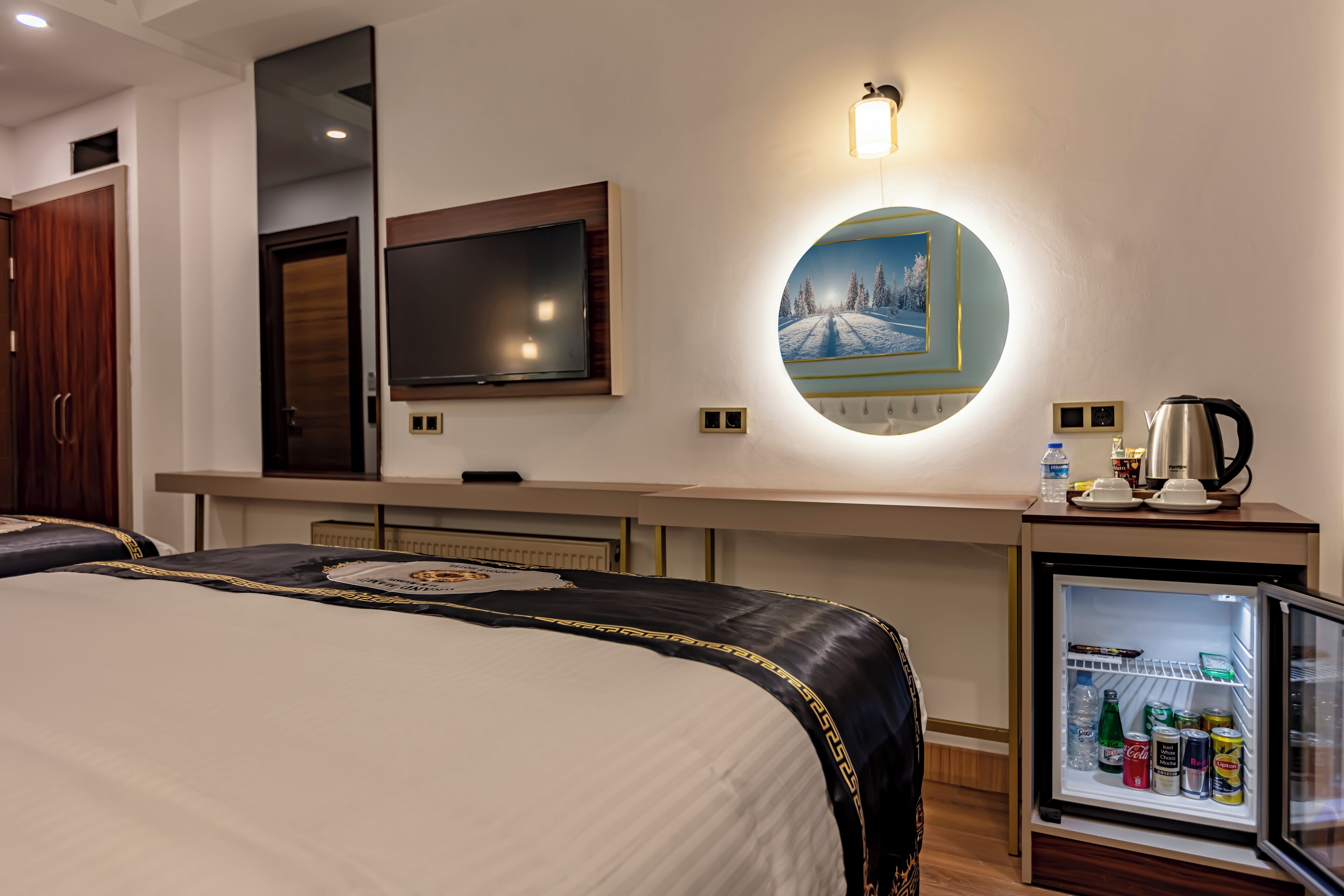 Habitación de hotel con cama, televisión, minibar y un cuadro en la pared.