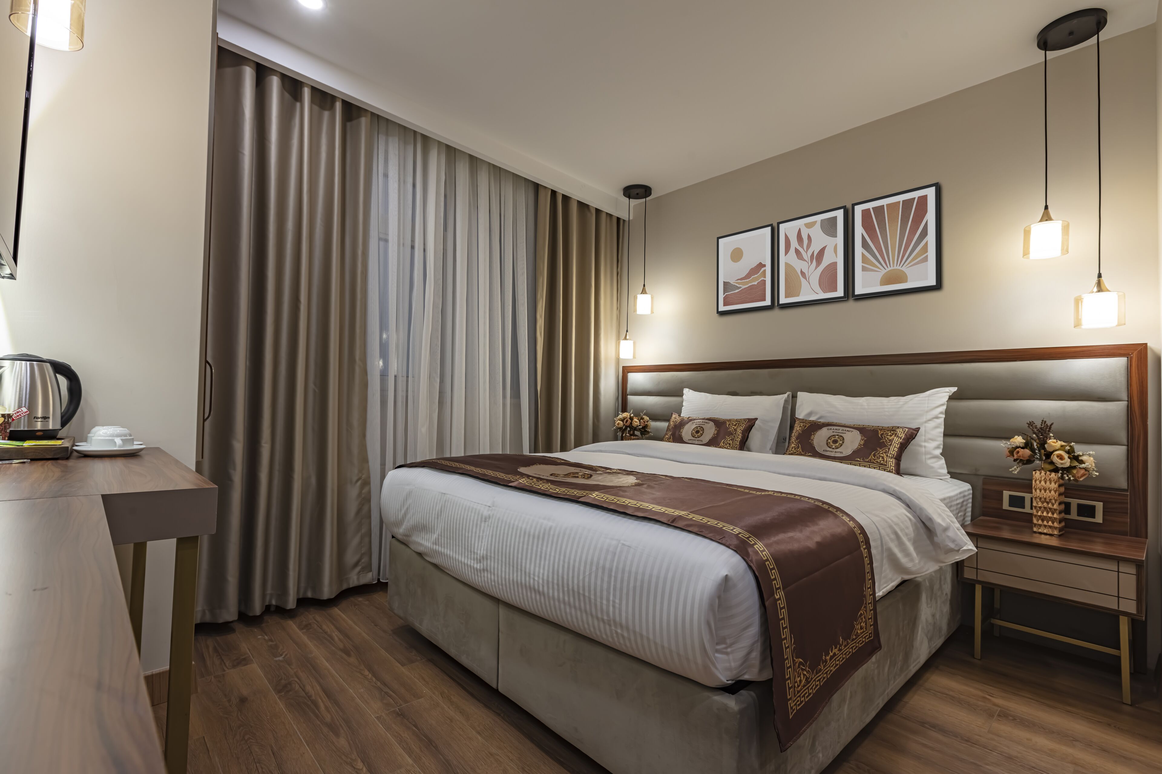 Habitació d'hotel ben ordenada, amb un llit gran, una taula de nit i una finestra amb cortines.