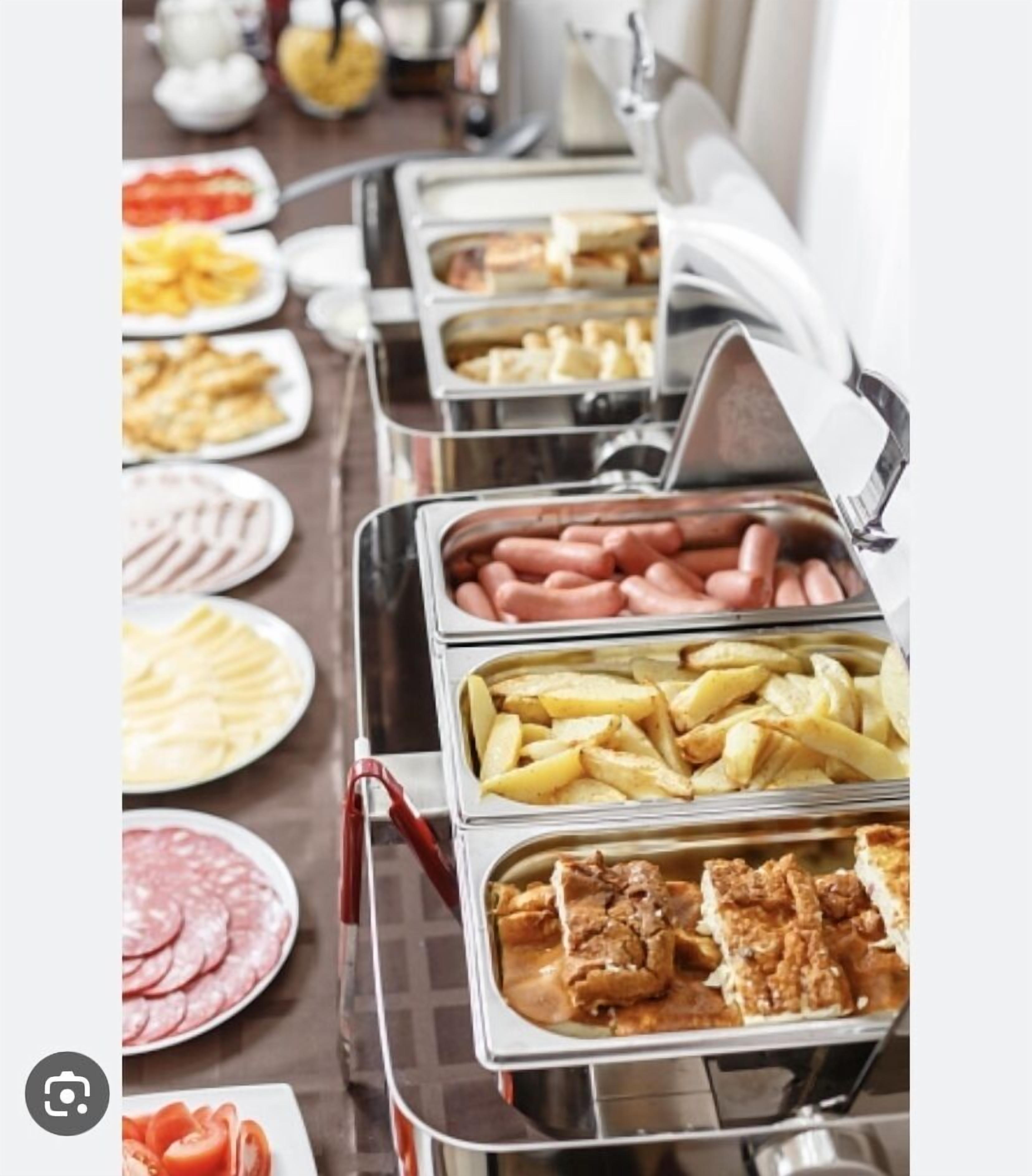 A buffet with various food items including hot dogs, French fries, and sliced meats.