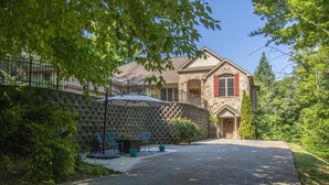 Une maison à deux étages avec une façade en pierre, un patio couvert avec des meubles d’extérieur et un mur en pierre.