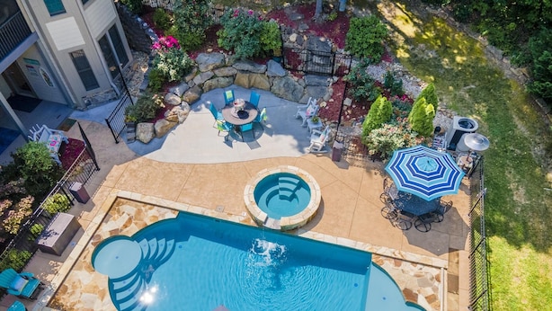 Un espace piscine aménagé sur le toit, comprenant un jacuzzi, des chaises longues et une table à manger.