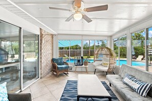 A sunroom with a ceiling fan, a pool view, and a seating area with a sofa and chairs. - Experience Navarre Beach just 7 mins away (Navarre)