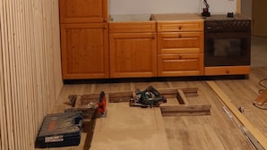 A kitchen with wooden cabinets, a built-in oven, and a workbench with tools. - Ferienwohnung Brunow ,,kerstin" In der Natur Zuhause (Neundorf(bei Schleiz))